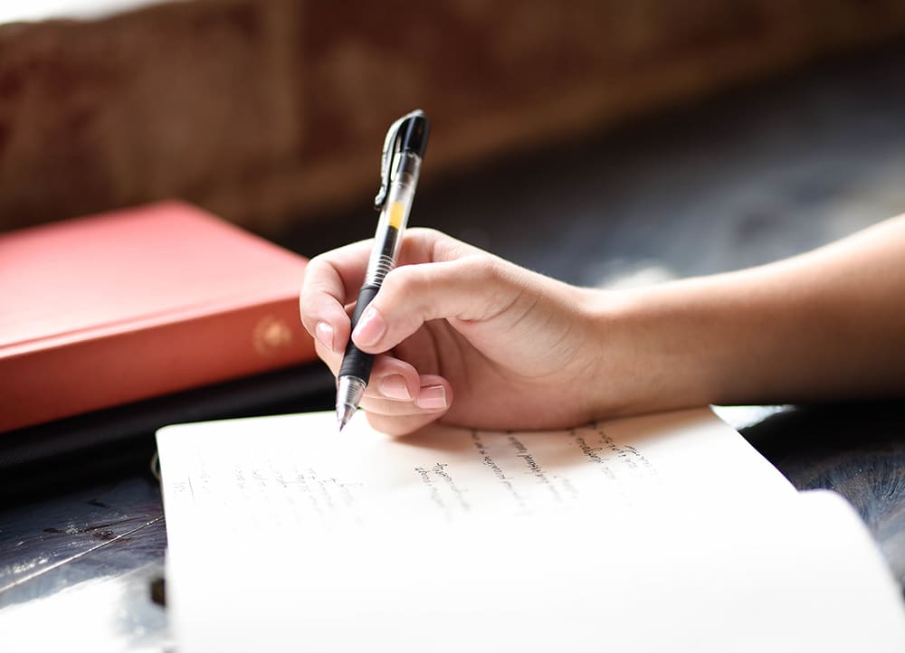 Photo by Hannah Olinger on Unsplash A person writing on paper with a pen.