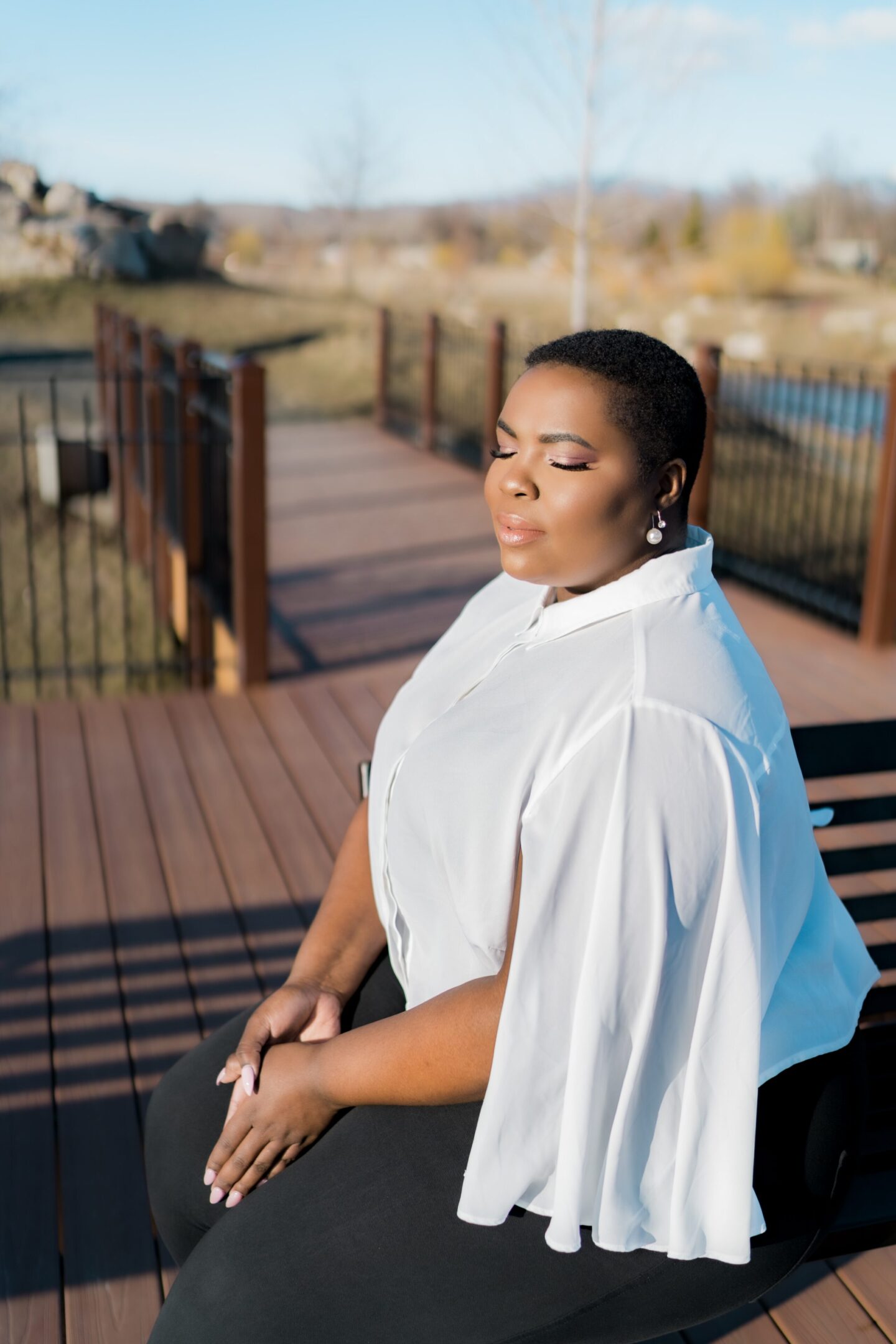 A woman in white shirt sitting on bench near railing.