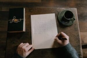 A person writing on paper with a pen.