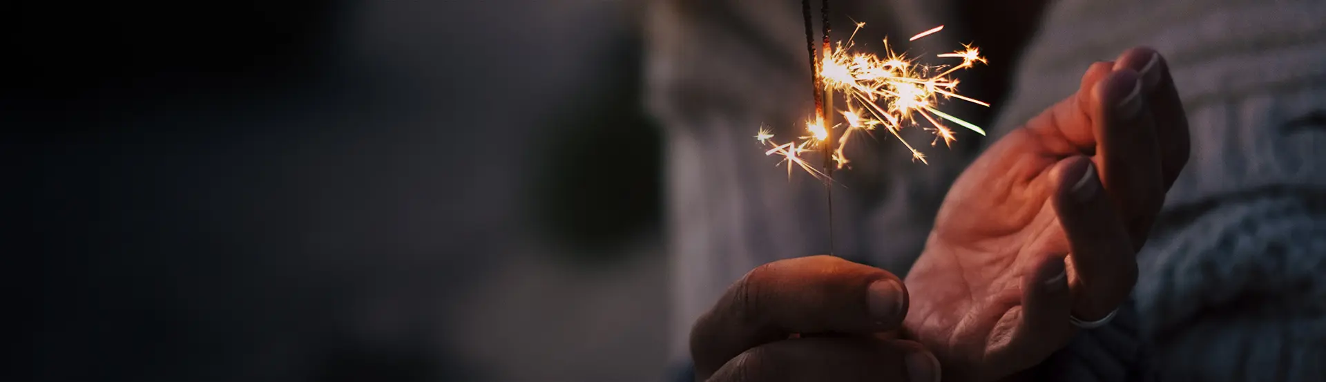A person holding sparklers in their hand.